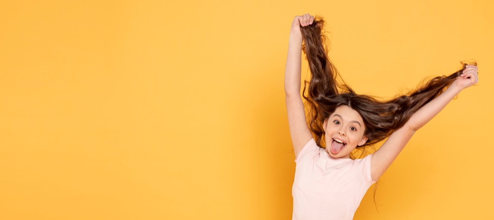 Fille étire cheveux grimace fond jaune